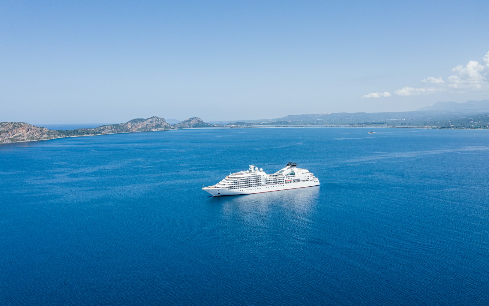 A cruise ship anchored off a sunlit coastline